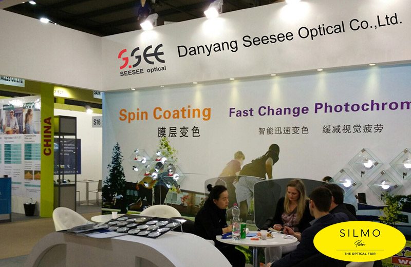 Seesee booth at SILMO in Paris with a wall reading Spin Coating and Fast Change Photochromic, visitors seated at a table