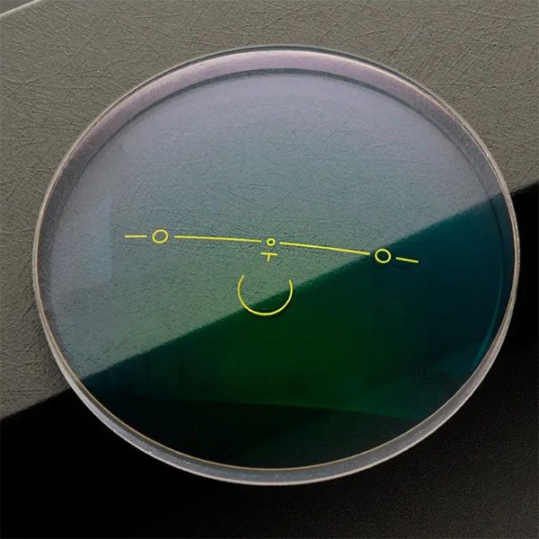An anti-fatigue lens with yellow engraving marks lying on a dark surface