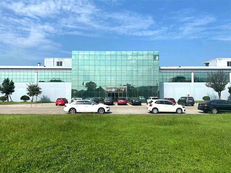 The Seesee office building with green glazing, cars parked on the forecourt and a lawn in front