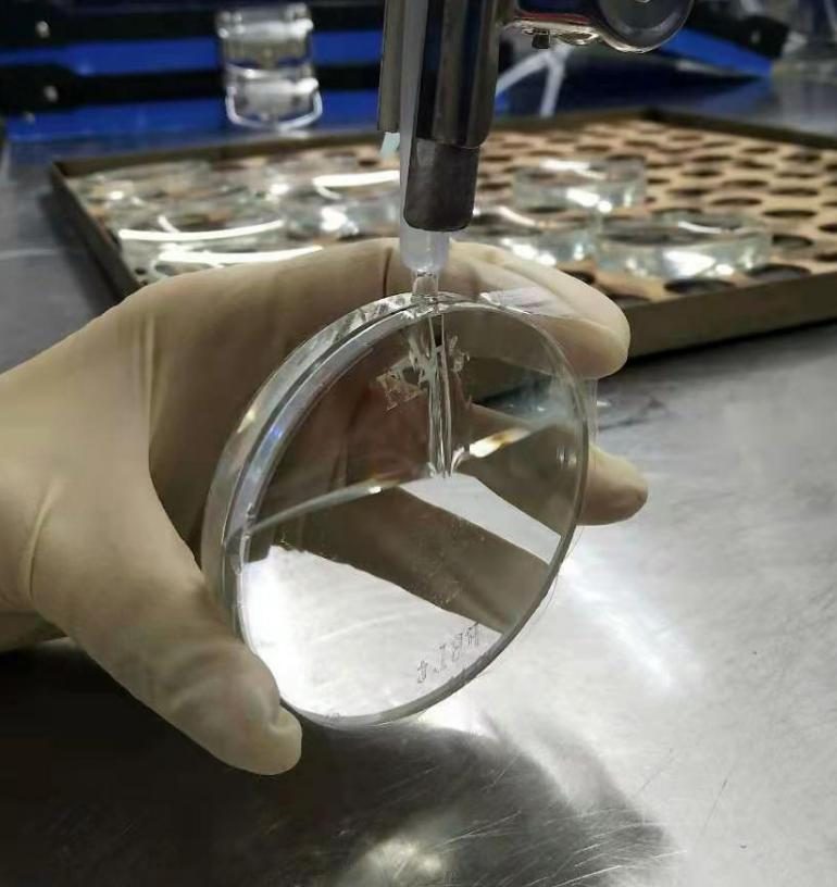 A gloved hand holding a filled mould assembly over a steel tray